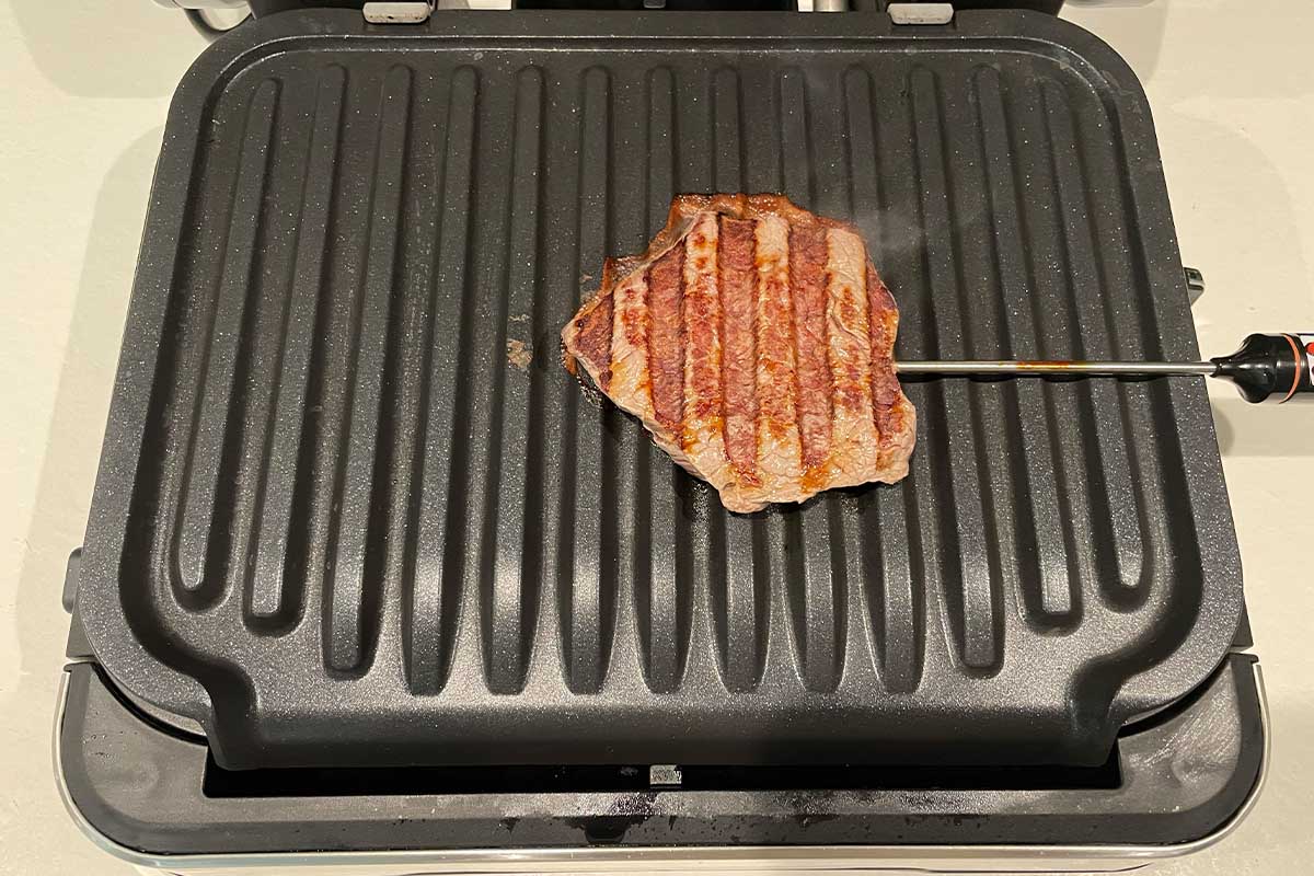 Ein gegrilltes Filet-Steak auf der Garplatte des Tefal-Kontaktgrills mit Bratenthermometer.