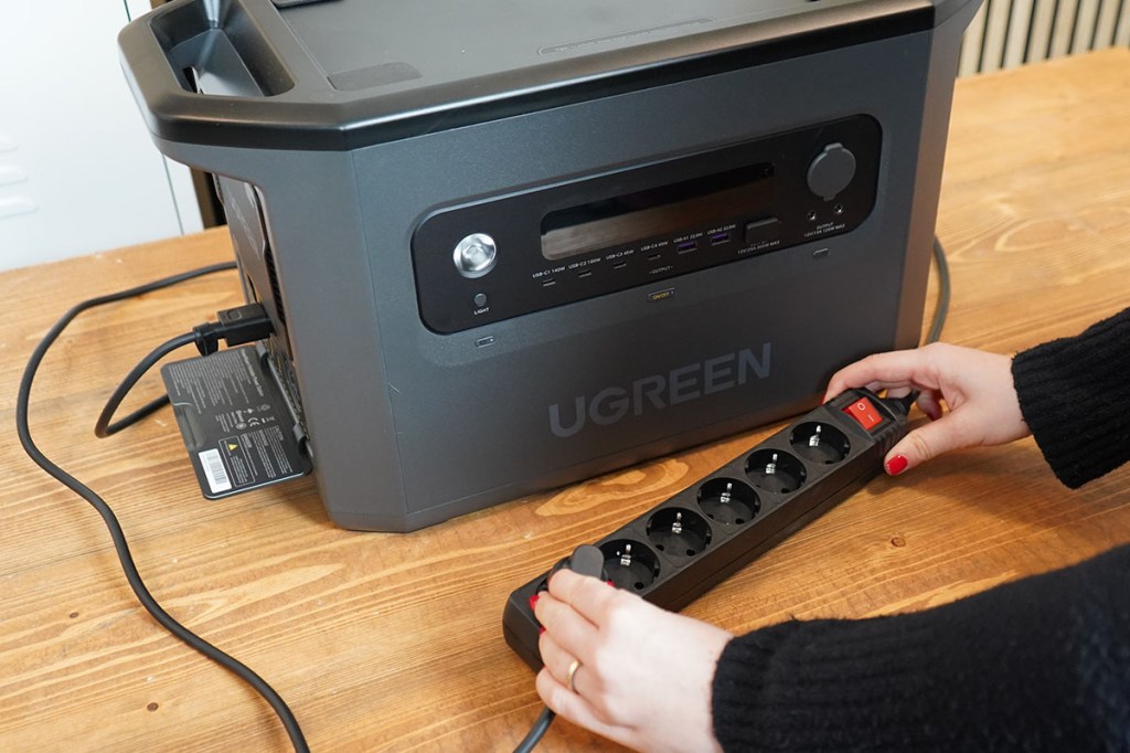 Eine Person steckt das Kabel der Ugreen Powerstation in eine Mehrfachsteckdose.