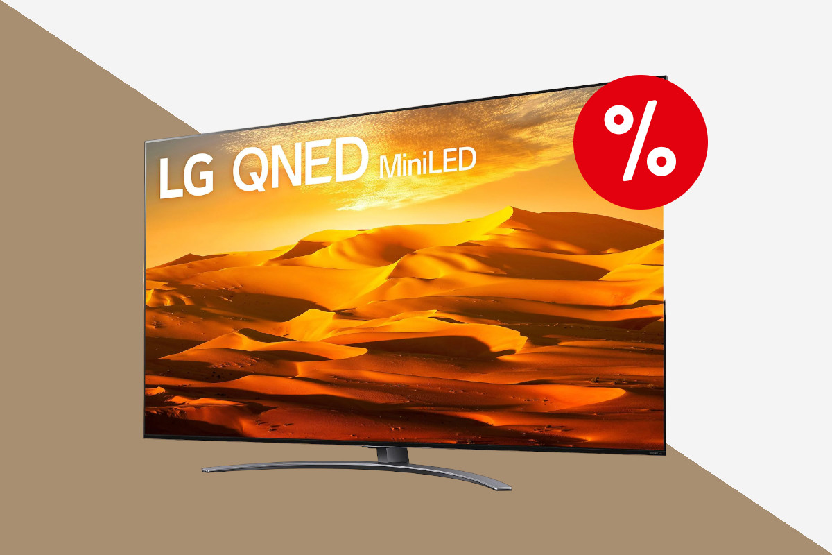 LG-Fernseher schräg von vorne auf Standfuß zeigt orange goldenes Wüstenbild auf weiß bronzenem Hintergrund mit rotem Prozentbutton oben rechts
