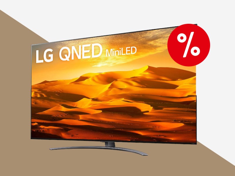 LG-Fernseher schräg von vorne auf Standfuß zeigt orange goldenes Wüstenbild auf weiß bronzenem Hintergrund mit rotem Prozentbutton oben rechts