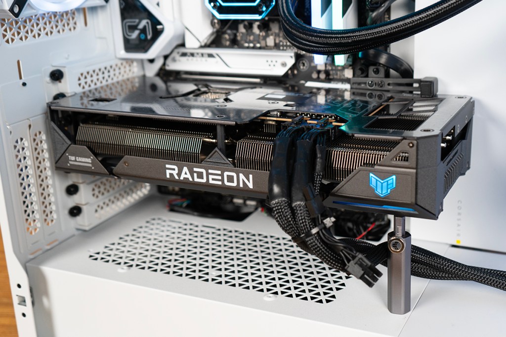 Die silbergraue Grafikkarte ASUS TUF Gaming Radeon 7800 XT OC im Testsystem fotografiert. Die RGB-Beleuchtung strahlt blau.