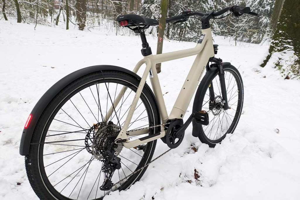 weißes E-Bike von schräg hinten fotografiert, im Schnee stehend