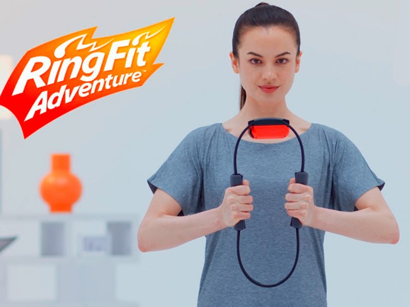 Man sieht eine Frau im grauen Shirt, die einen Pilates-Ring in den Händen hält und damit Sport macht.