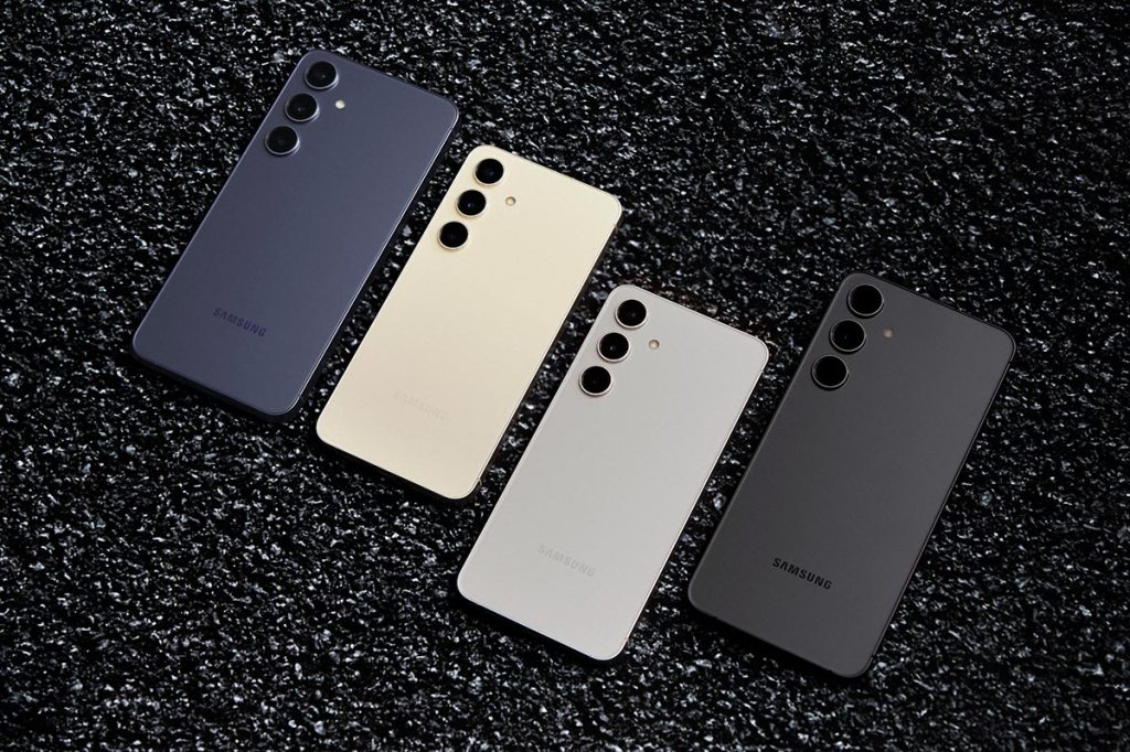 Vier Samsung Galaxy S24 Smartphones auf einem dunklen Hintergrund liegend.