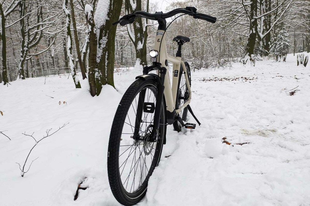weißes E-Bike von vorne im Schnee stehend