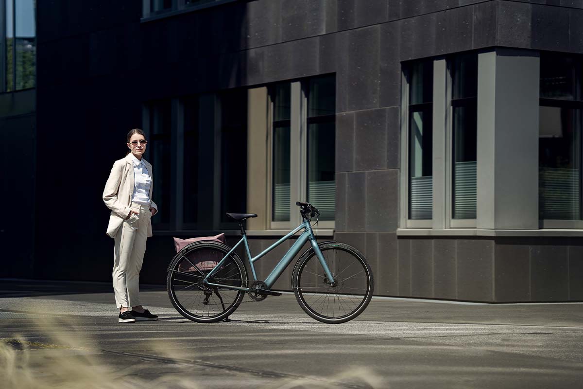 Frau in einer städtischen Umgebung, sieht steht neben einem E-Bike