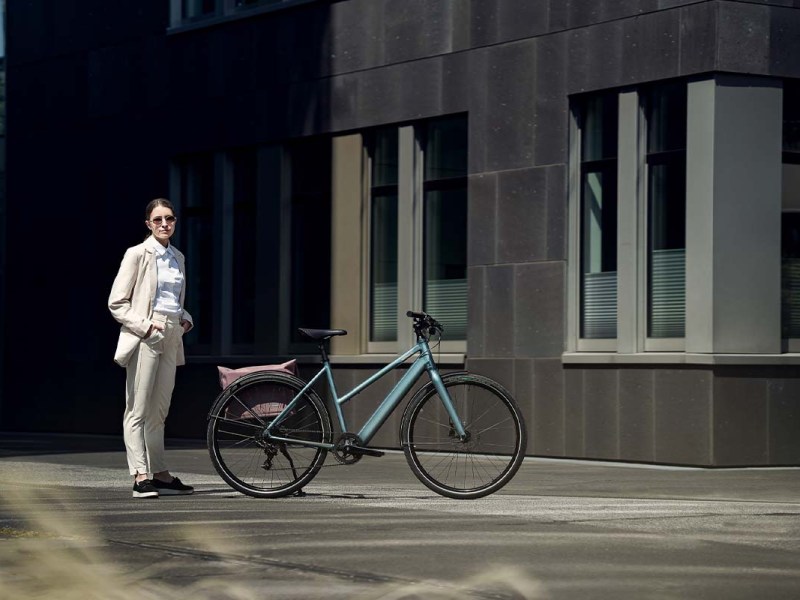 Frau in einer städtischen Umgebung, sieht steht neben einem E-Bike