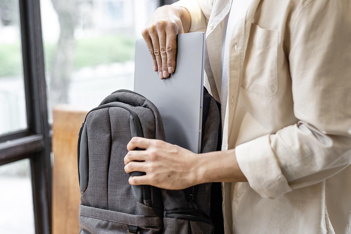 Person, die einen Laptop im Rucksack verstaut.