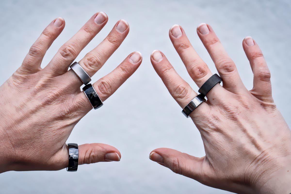 Zwei Hände, an denen insgesamt fünf Smarte Ringe stecken.