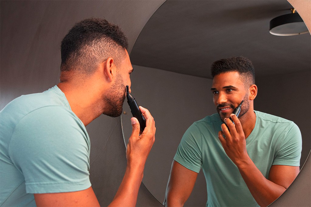 Ein Mann vor einem Spiegel der einen Beurer Haartrimmer benutzt.