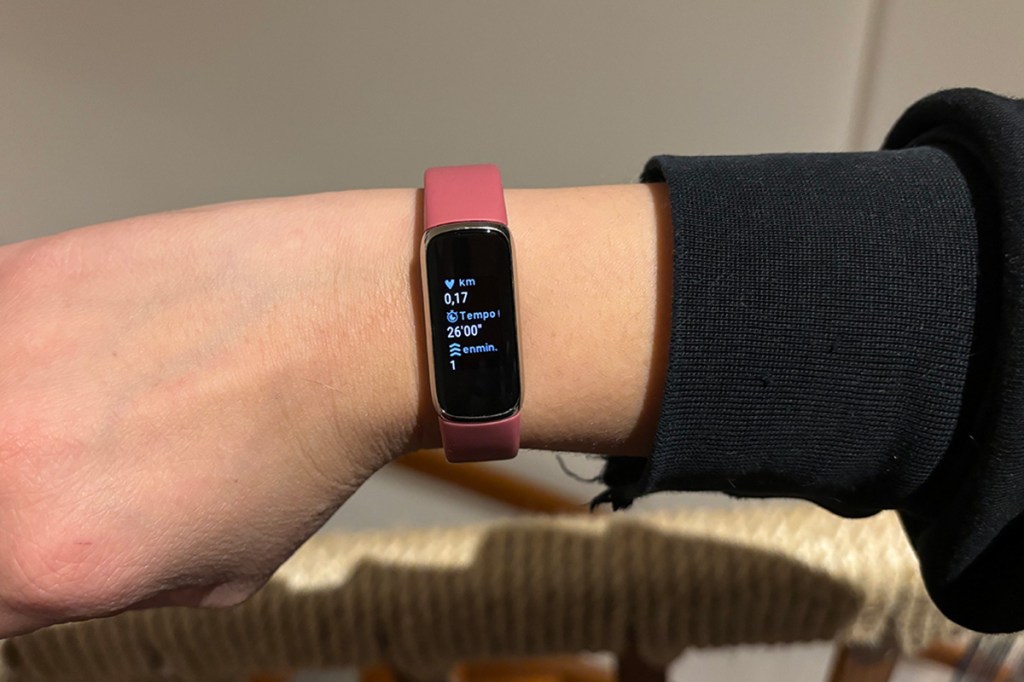 Foto einer Frauenhand, mit dem Fitness-Tracker Fitbit Luxe am Handgelenk. Im Hintergrund ein Treppengeländer.
