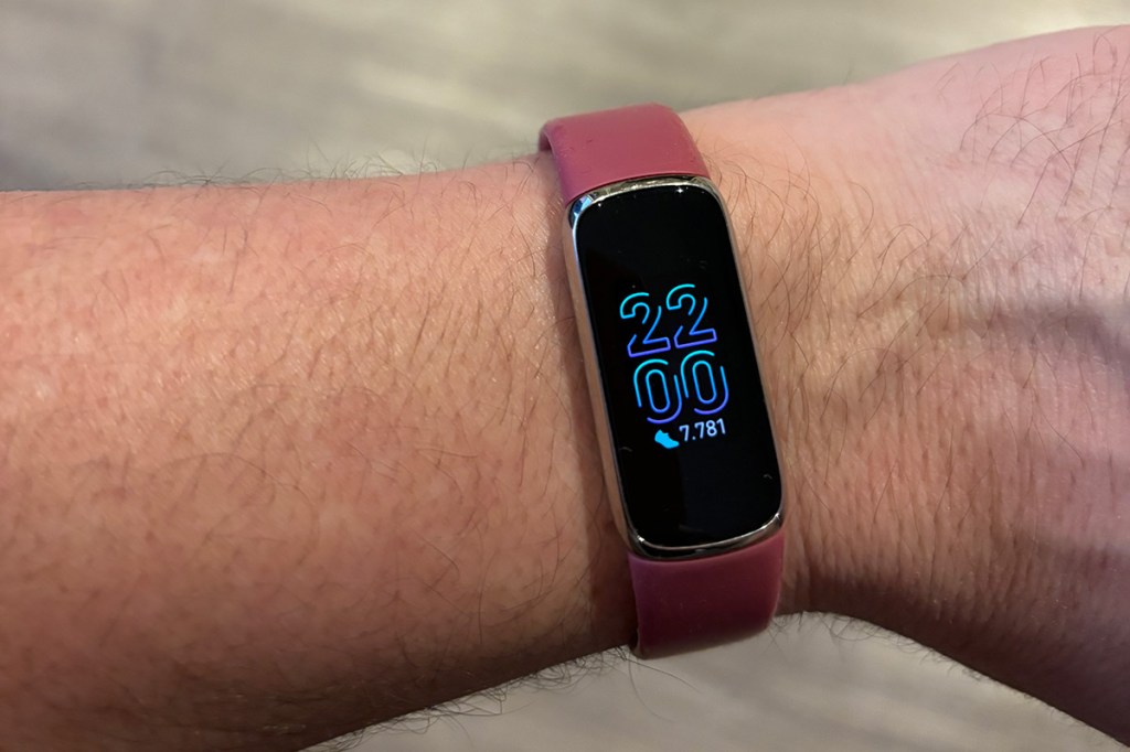 Foto einer Männerhand, mit dem Fitness-Tracker Fitbit Luxe am Handgelenk. Zu sehen ist ein modernes Digital-Ziffernblatt.
