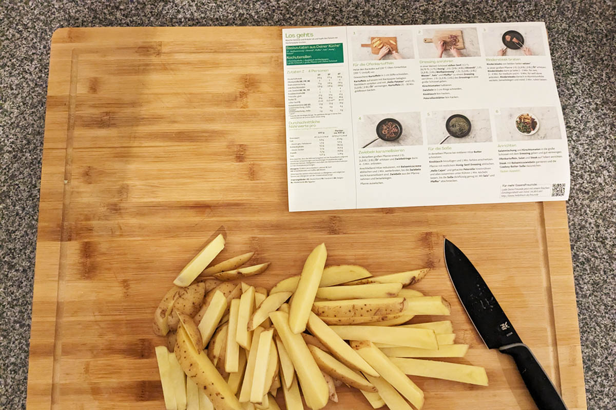 Kartoffelstücke und ein Messer liegen auf einem Brett