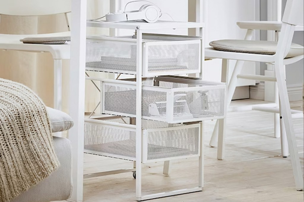 Ein weißes IKEA-Schubladenelement steht unter einem Schreibtisch.