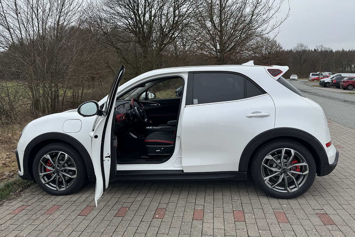 E-Auto GWM Ora 03 GT auf Parkplatz. Direkte Ansicht im Profil, mit geöffneter Fahrertür.