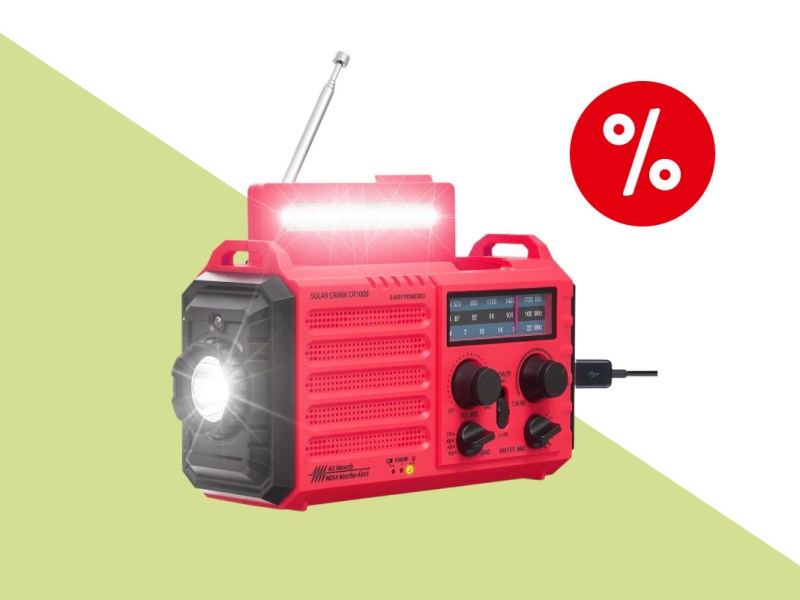 Rot schwarzes Kurbelradio schräg von vorne mit strahlender runder Lampe an der Seite und länglicher Leuchte oben, auf limonengelb weißem Hintergrund mit rotem Prozentbutton oben rechts