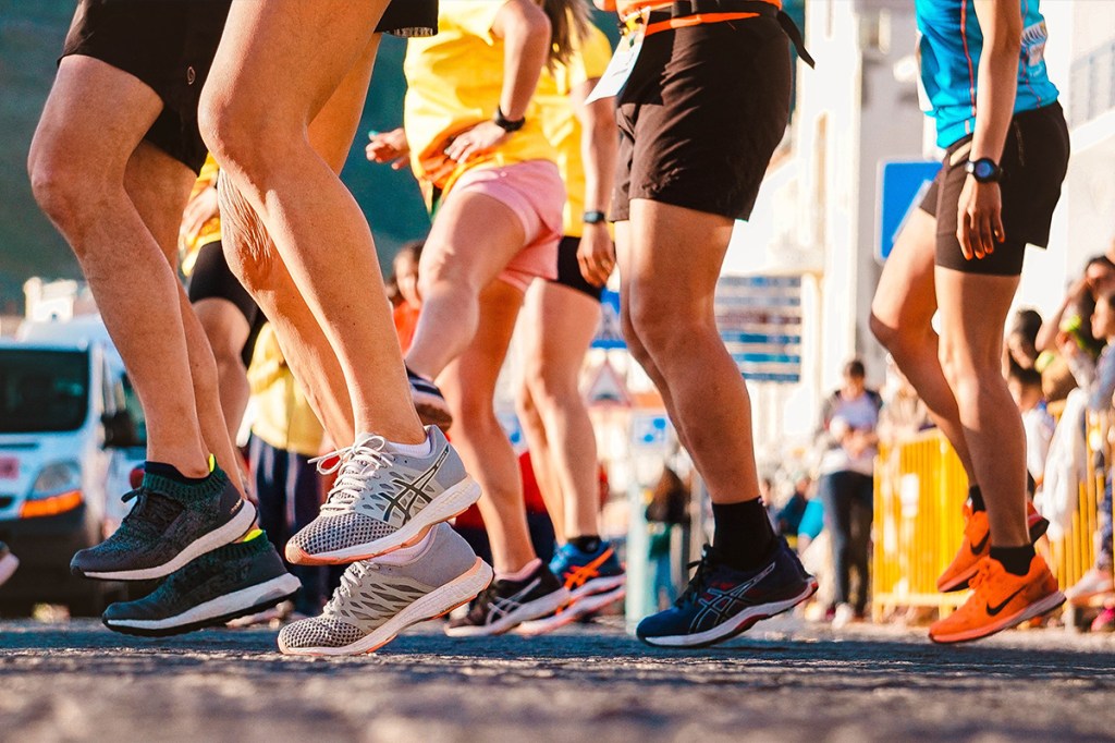 Eine Gruppe von Läufern im Sonnenschein. Man sieht nur Beine und Füße.
