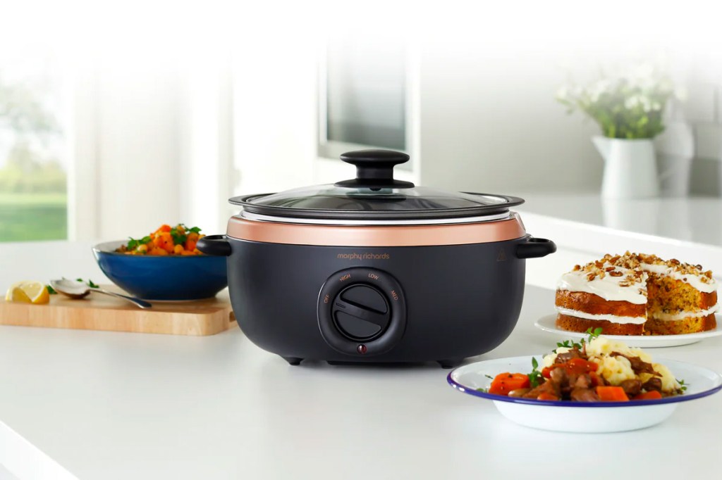 Der Slow Cooker von Morphy Richards steht auf einer Arbeitsfläche einer Küche mit verschiedenen Gerichten drum herum.