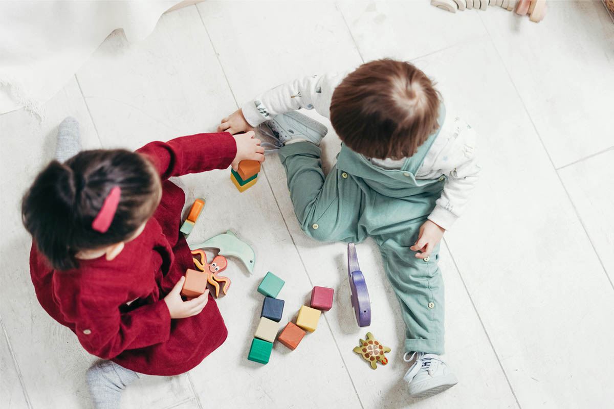 Zwei Kinder spielen mit bunten Bauklötzen