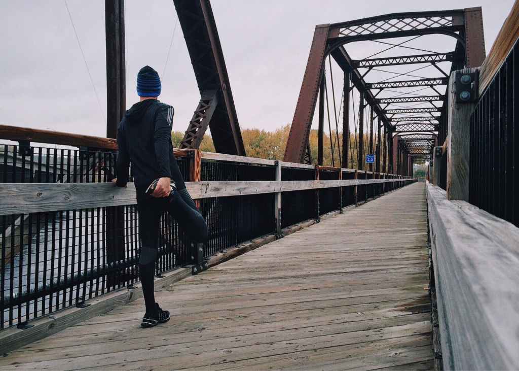 Ein Läufer legt auf einer Brücke eine Pause ein.