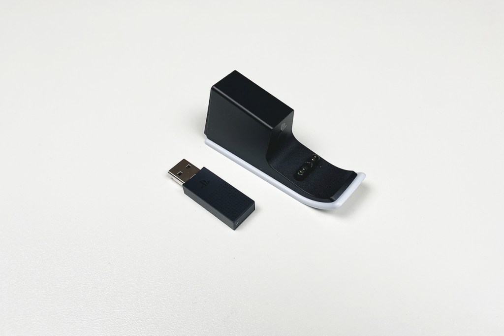 USB-Adapter und Ladehalterung des Pulse Elite auf weißem Hintergrund fotografiert.