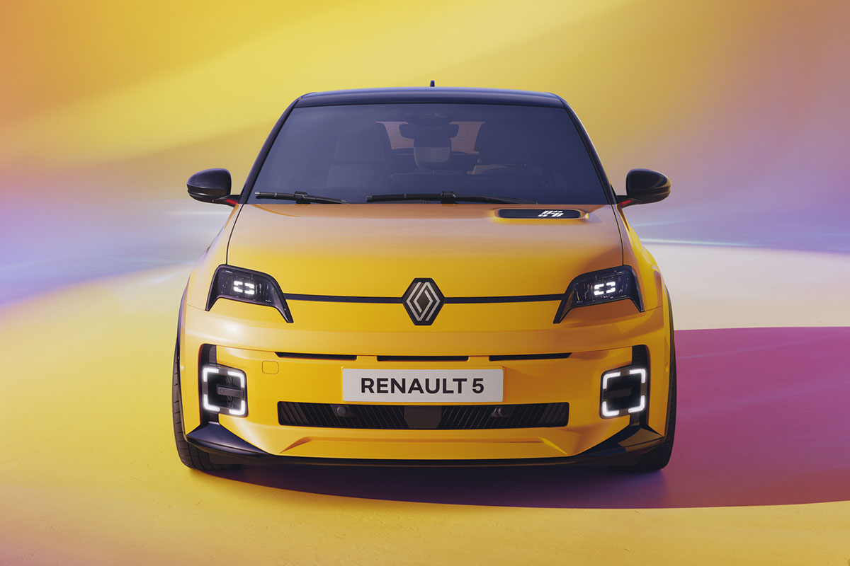 Gelber Renault 5 E-Tech Electric steht in Studiokulisse von vorn aus gesehen.