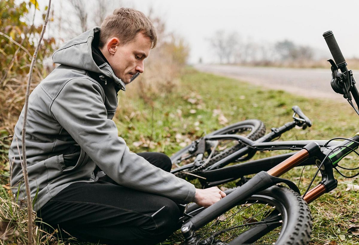 Mann hock am Straßenrand im Gras vor seinem E-Bike.