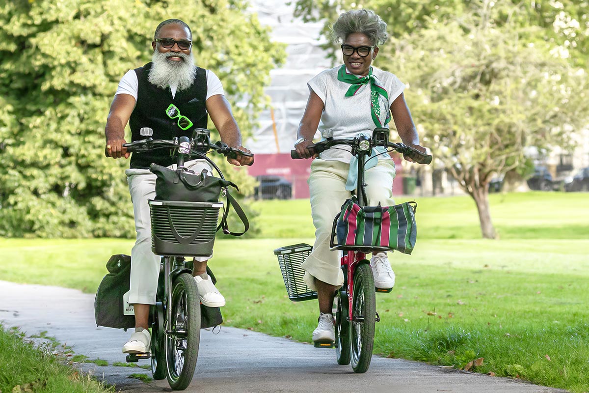 Zwei ältere Menschen auf einem E-Bike unter freiem Himmel.
