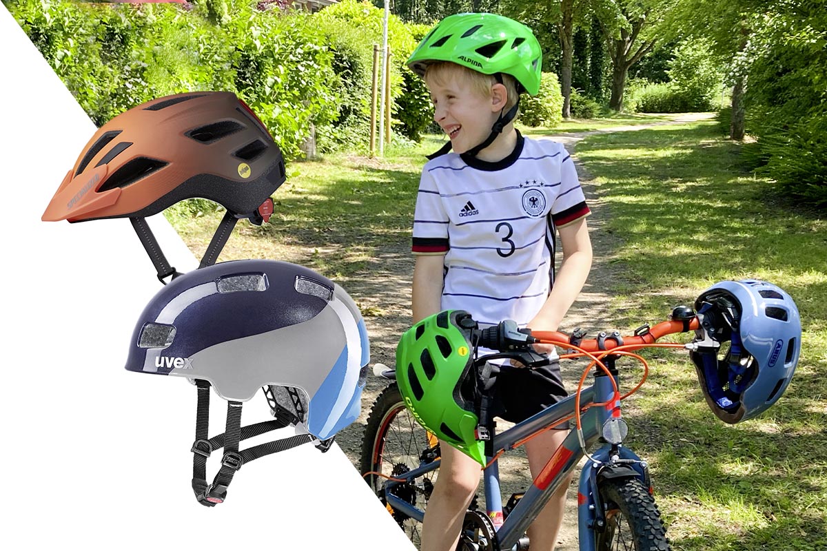 Kind mit Helm auf einem Fahrrad, an dem zwei weitere Helme hängen.