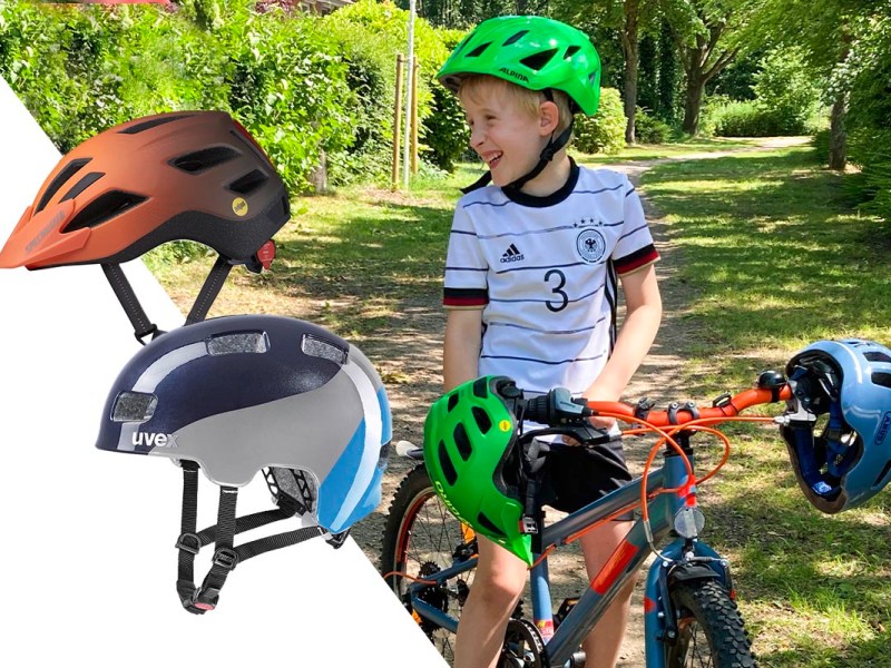 Kind mit Helm auf einem Fahrrad, an dem zwei weitere Helme hängen.
