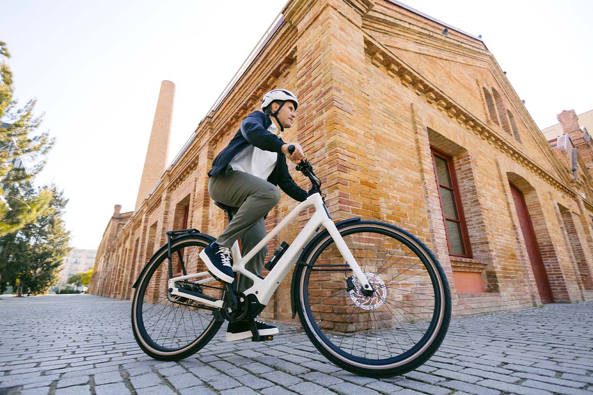 Fahrradfahrer fährt mit einem E-Bike, im Hintergrund ein Backsteingebäude