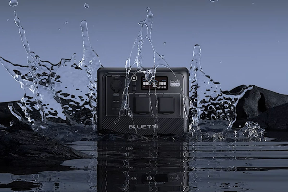Die AC60 von Bluetti auf einer nassen Fläche mit Wasserspritzern um sie herum.