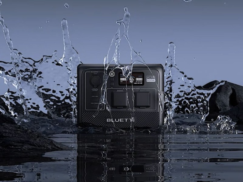Die AC60 von Bluetti auf einer nassen Fläche mit Wasserspritzern um sie herum.