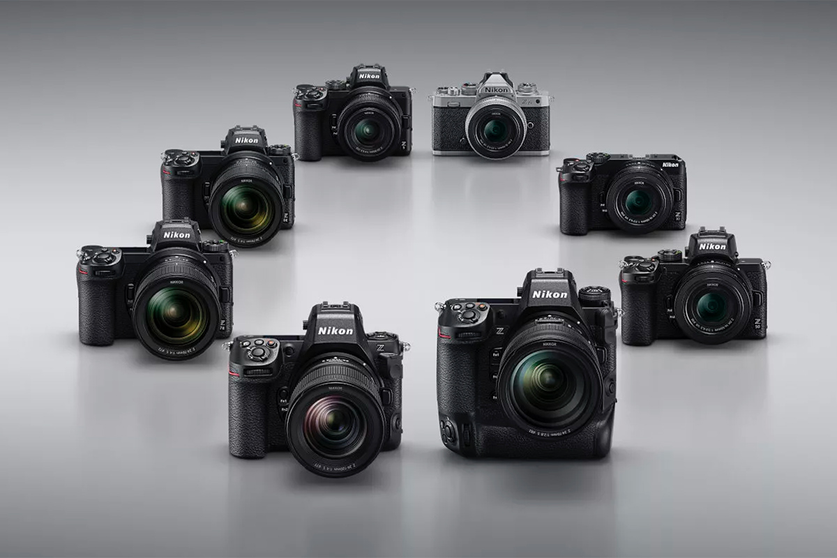 8 Nikon-Kameras vor silbergrauem Hintergrund.