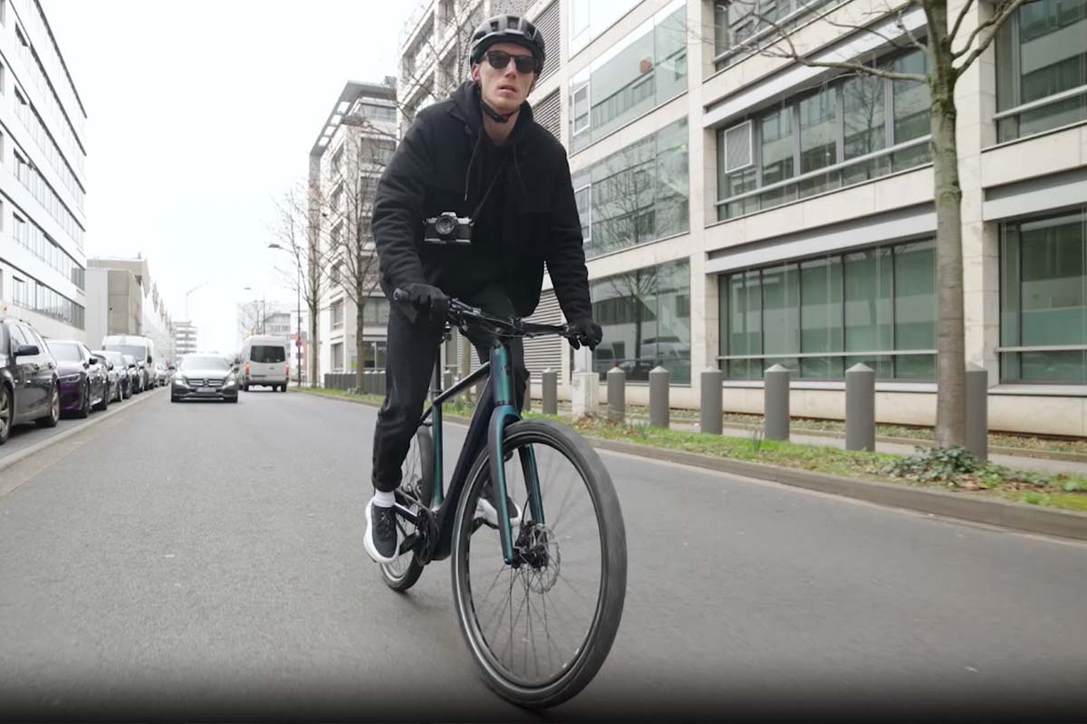 Mann fährt mit einem Rad durch die Stadt, man sieht in von vorne auf die Kamera zufahren