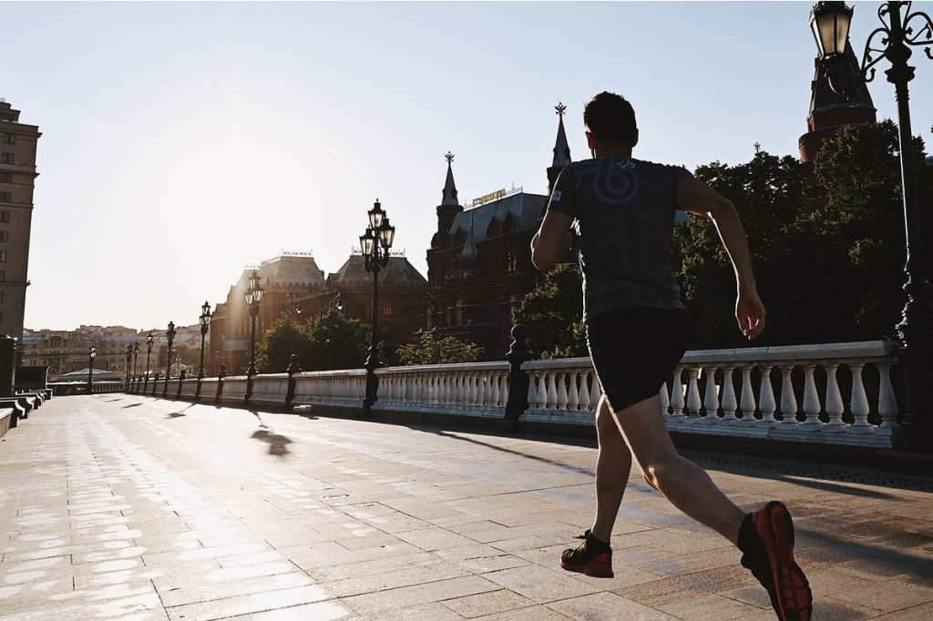Ein Mensch joggt bei aufgehender Sonnen über die Straße.