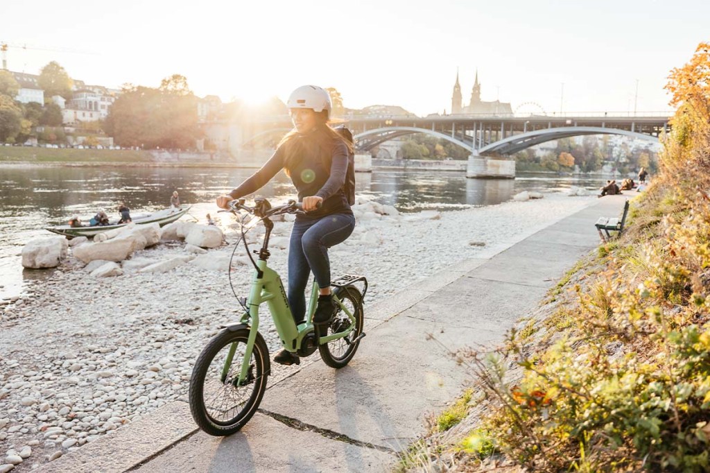 Frau fährt mit einem E-Bike an einem Fluss entlang