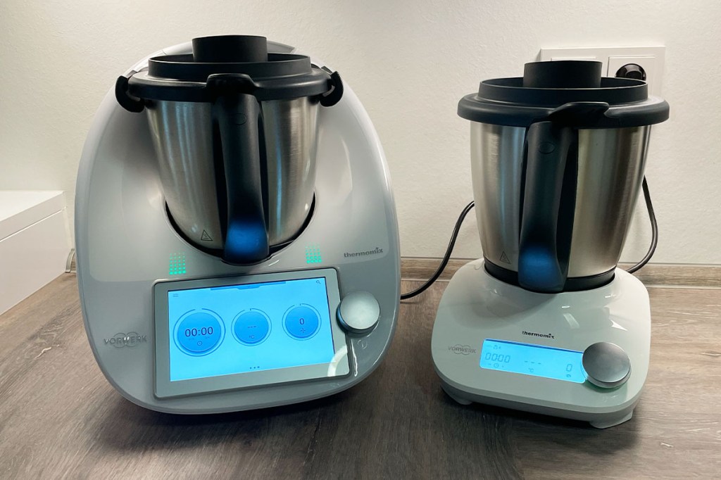 Der Thermomix TM6 neben dem Thermomix Friend, jeweils mit Mixtopf, auf einer Arbeitsfläche.