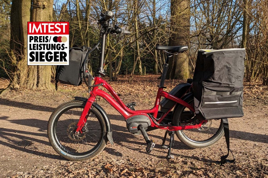 Rotes E-Bike in einem Park stehend, dazu ein Preis-Leistungs-Siegel