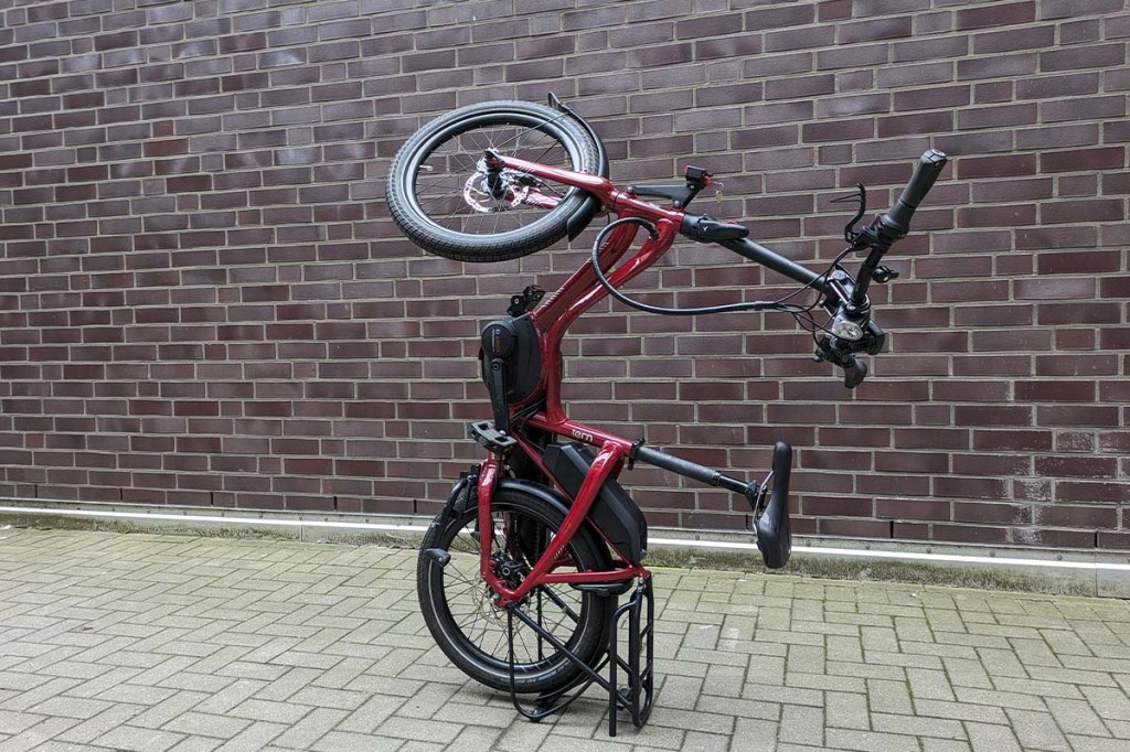 E-Bike, welches aufrecht geparkt vor einer Mauer steht