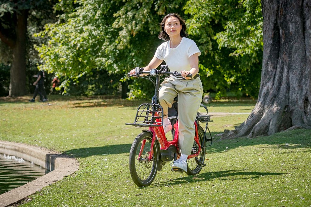 Frau fährt auf einem roten Fahrrad durch einen Park