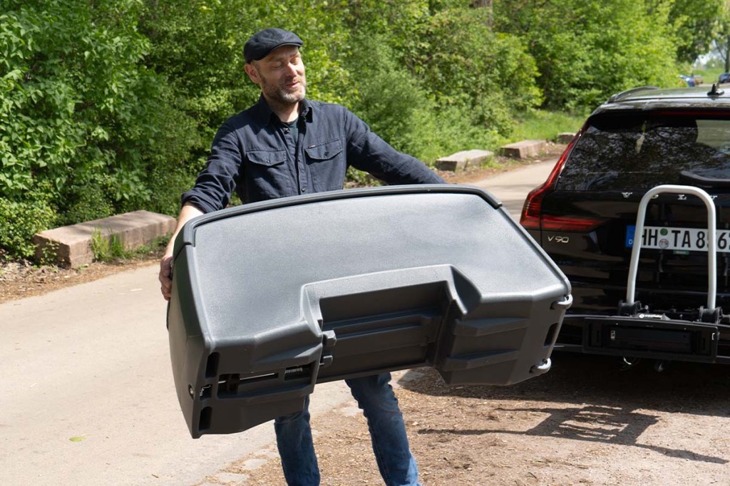 Mann trägt eine Autotransportbox