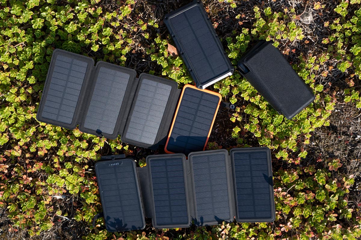 Vier Solar-Powerbanks auf einer Wiese liegend.