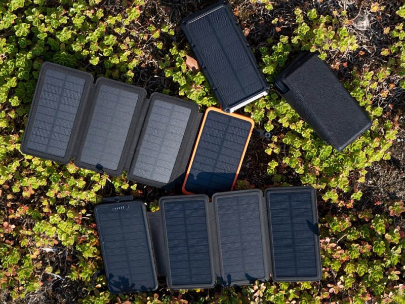 Vier Solar-Powerbanks auf einer Wiese liegend.