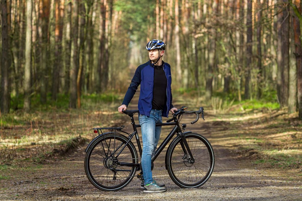 Mann steht mit einem E-Bike in einem Wald