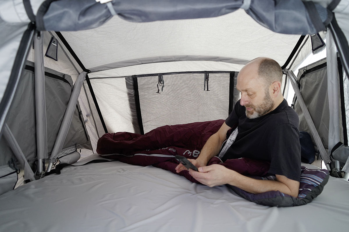 Mann liegt in einem Schlafsack in einem Dachzelt.