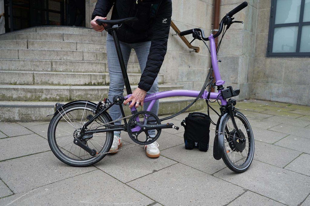 Person steht hinter einem kleinen, lilafarbenen Fahrrad