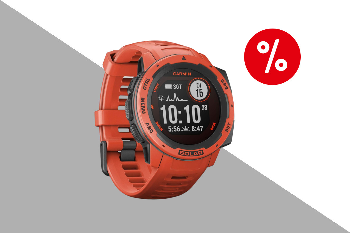 Garmin Instinct Solar in orange mit dunklem Display das digitale Uhr anzeigt schräg von vorne mit geschlossenem Armband auf hellgrau weißem Hintergrund mit rotem Prozentbutton oben rechts