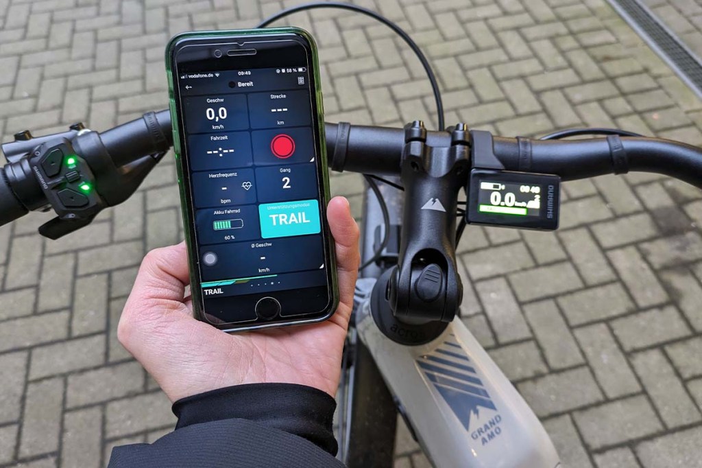Smartphone mit Shimano App wird neben den Lenker eines E-Bikes gehalten