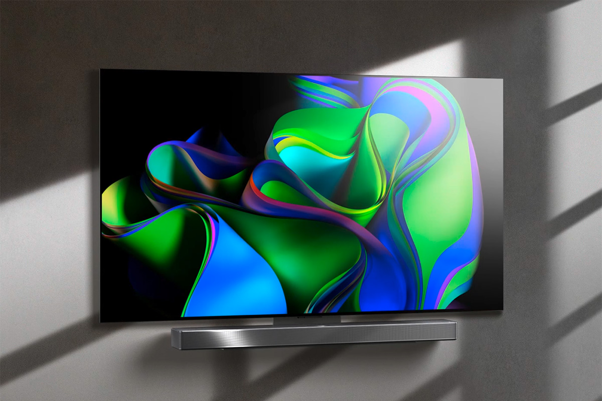 Fernseher mit bunten Farbwirbeln auf dem Display, an einer grauen Wand aufgehangen.